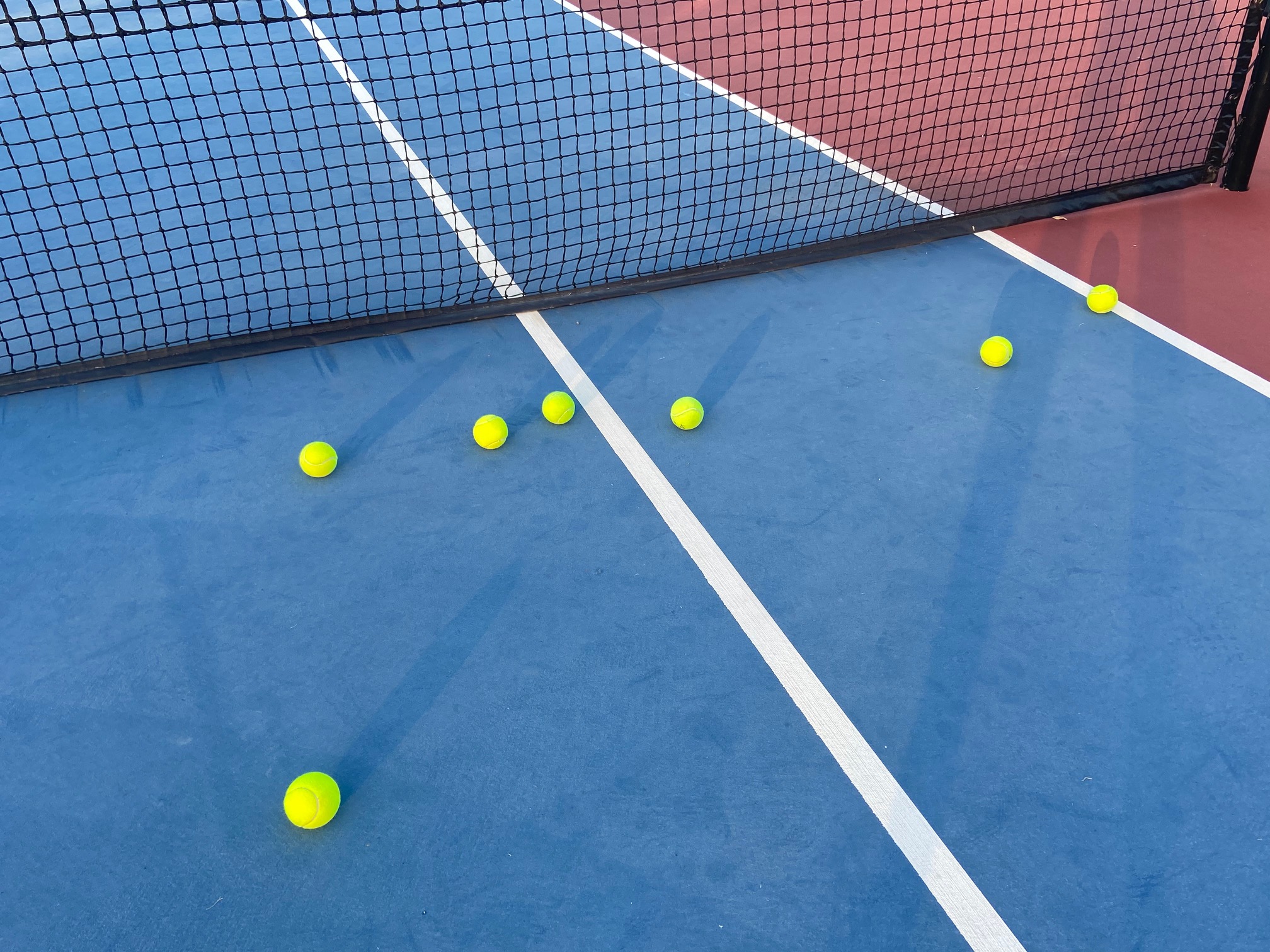 Tennis Balls Next To a Net