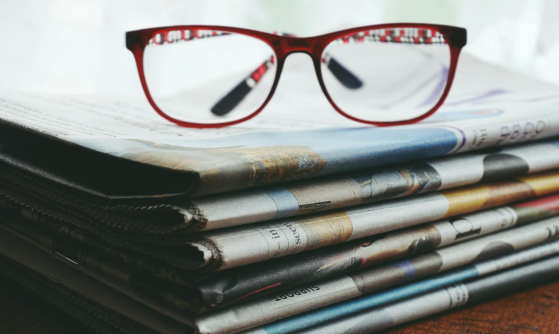 red framed eyeglasses on newspapers