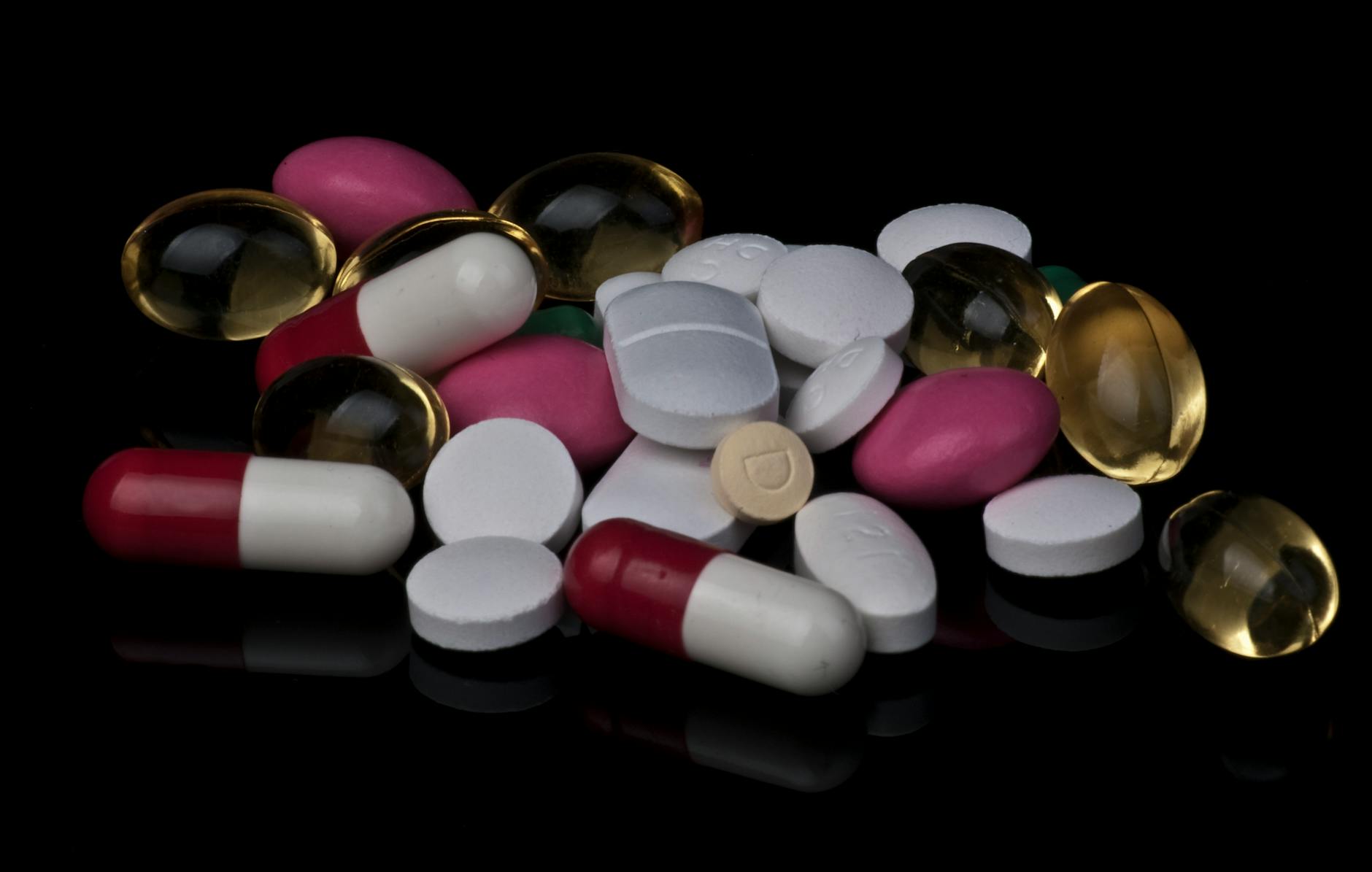 assorted pills and tablets piled on a black surface
