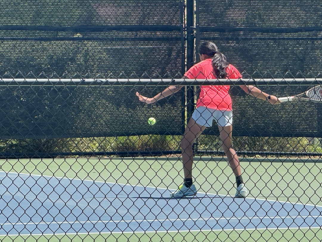 Girl in red shirt hits ball.