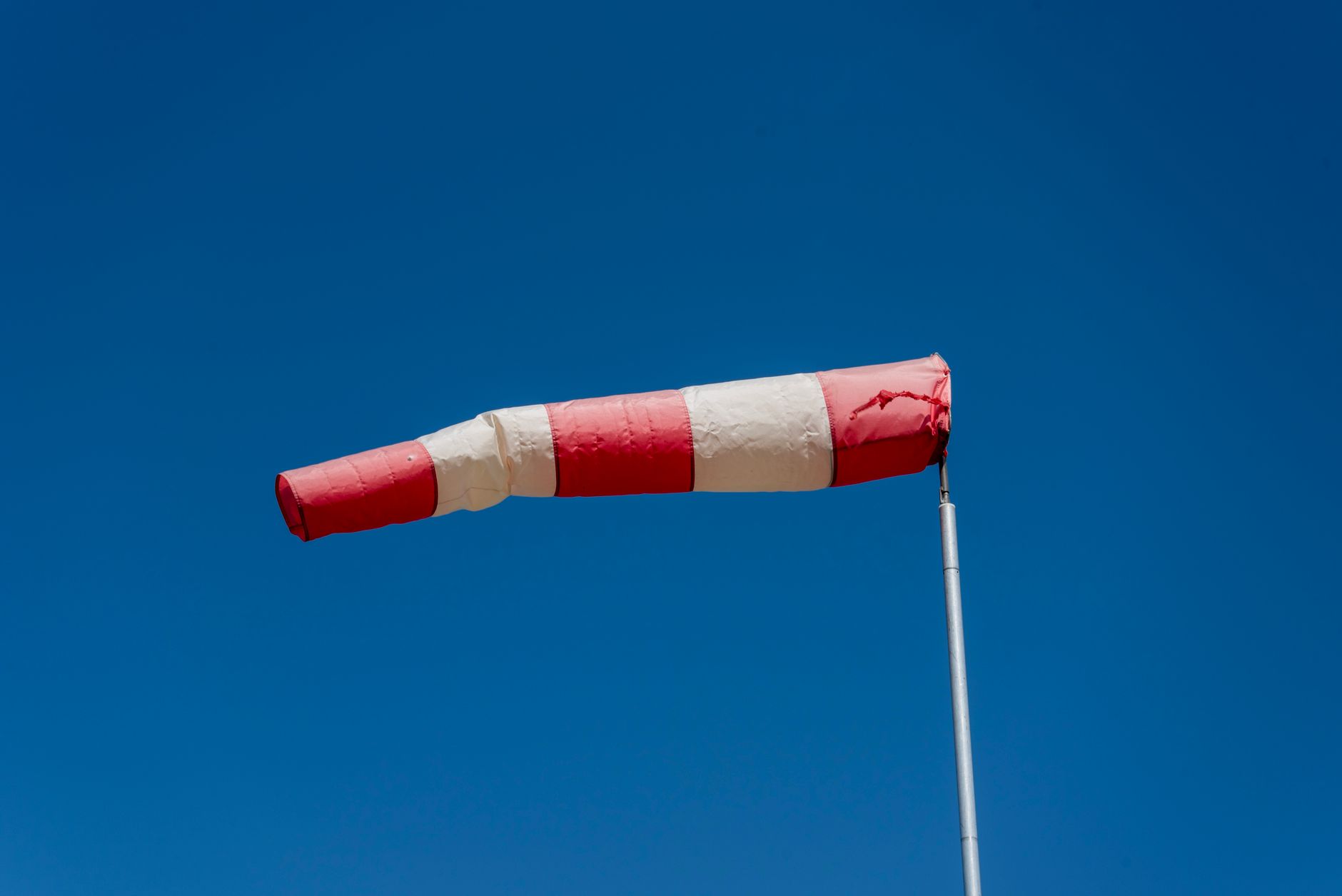 red and white windsock against clear blue sky