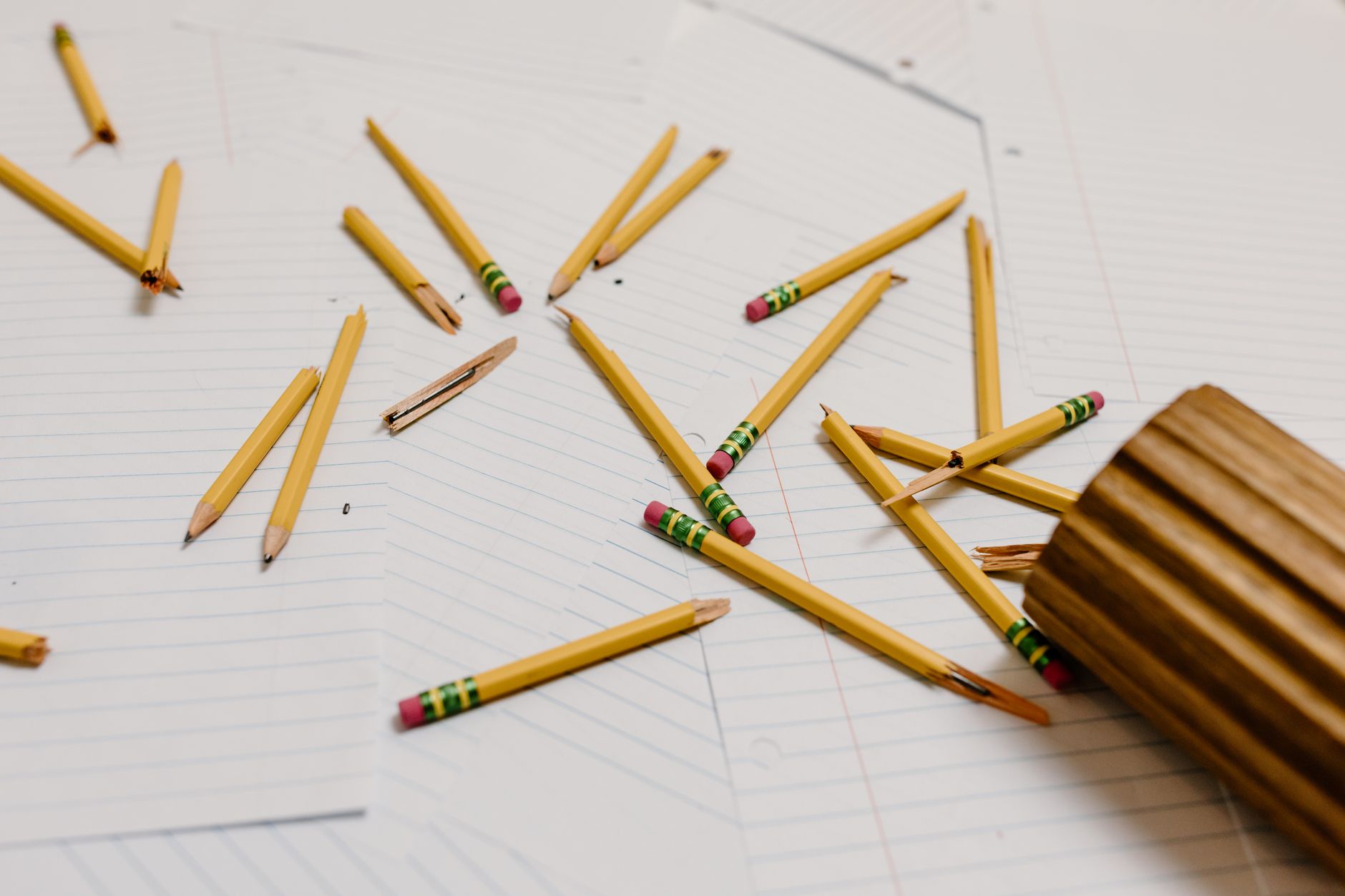 broken wooden pencils on top of blank sheets of paper